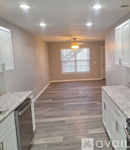 A kitchen with white cabinets and a marble countertop.