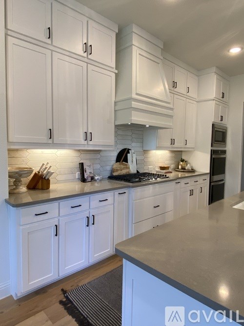 A kitchen with white cabinets and a grey countertop.