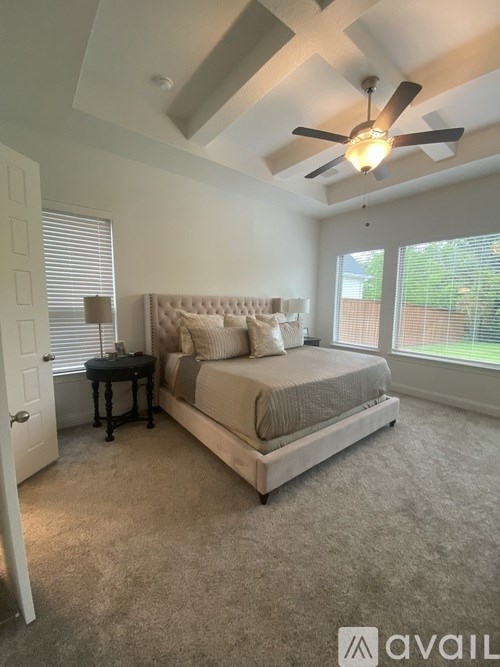 A bedroom with a large bed and a ceiling fan.