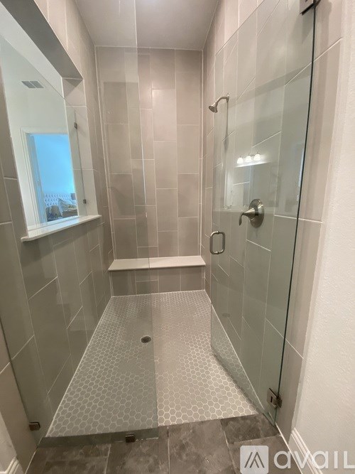 A bathroom with a walk in shower and a window.