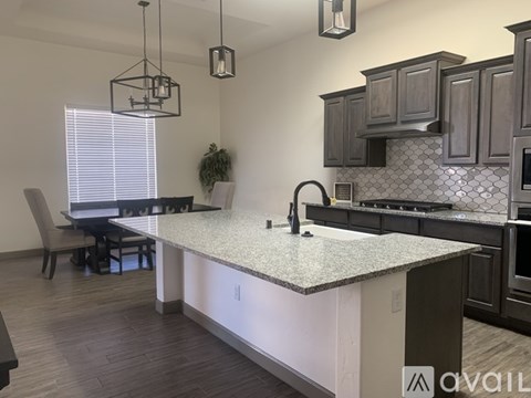 A kitchen with a granite countertop and dark cabinets.