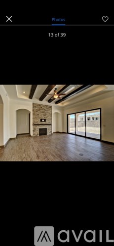 A spacious room with a stone fireplace and wooden flooring.