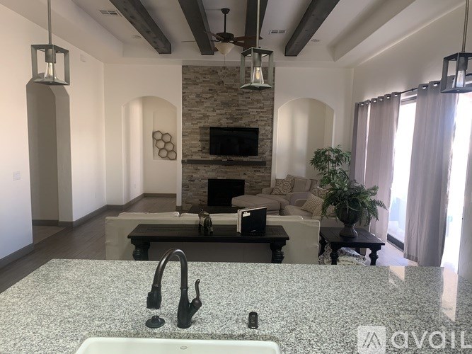 A kitchen with a granite countertop and a stone fireplace in the background.