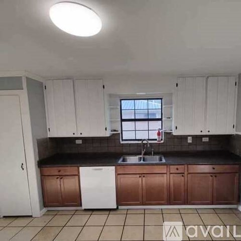 A kitchen with white cabinets and brown countertops.