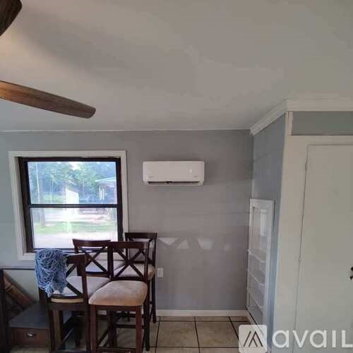 A room with a window, a chair, and a fan.