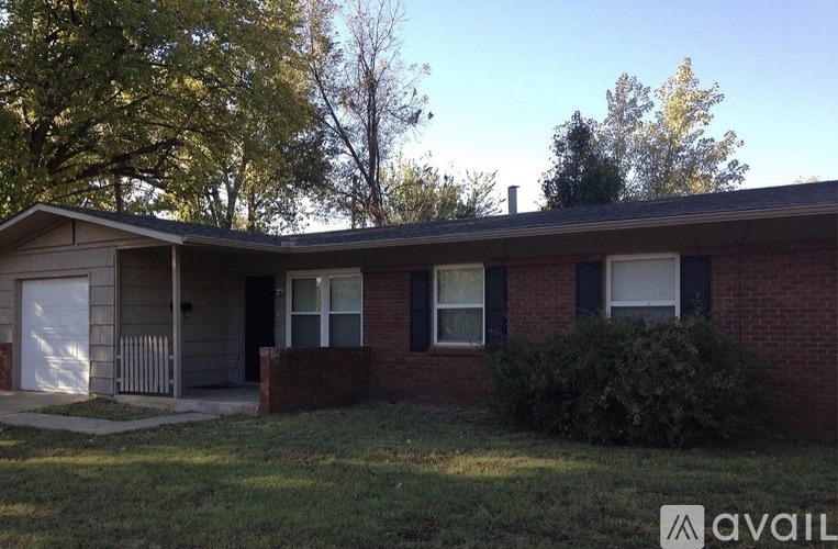 A house with a brick facade and a white garage door is for sale.