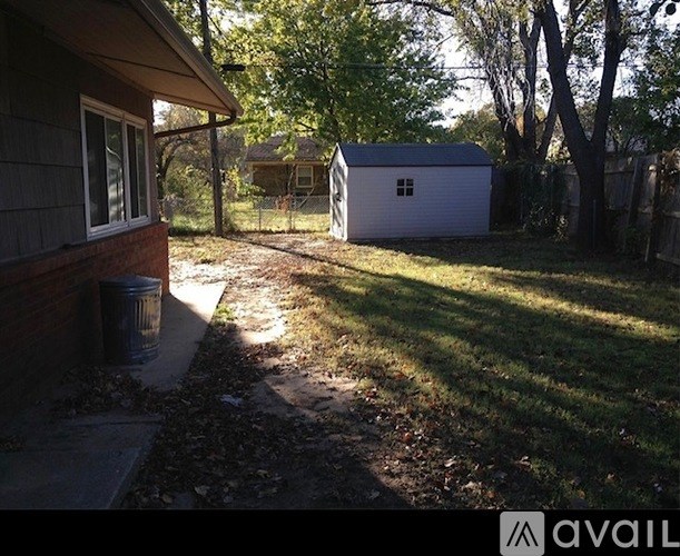 A backyard with a shed and a trash can.