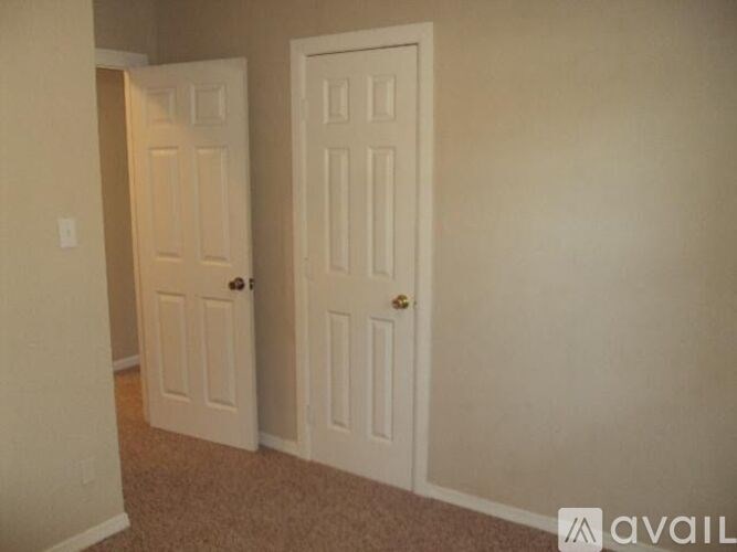 Two white doors in a room with carpeted floor.