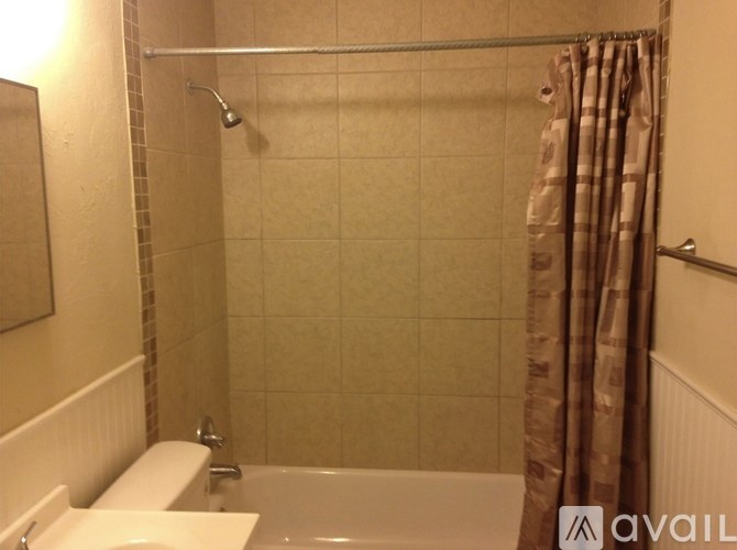 A bathroom with a white tub and brown shower curtain.