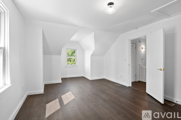 A spacious room with wooden flooring and white walls.
