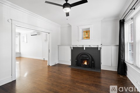 A living room with a fireplace and a ceiling fan.