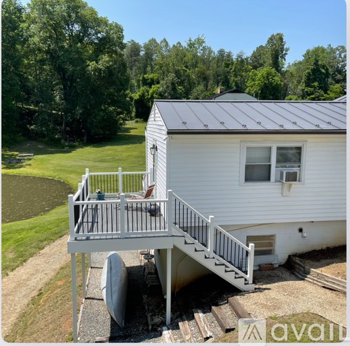 A white house with a grey roof and a deck.