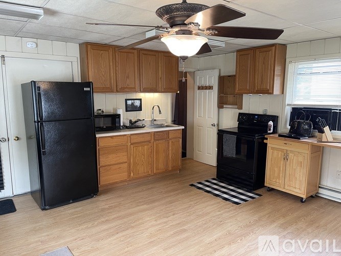 A kitchen with black appliances and wooden cabinets.