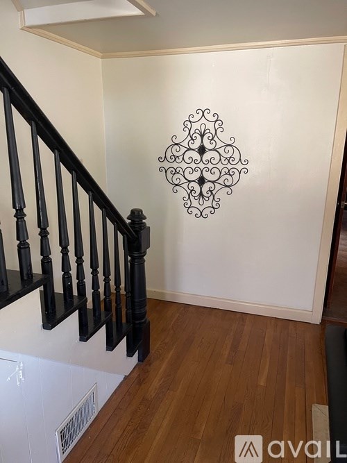 A staircase with a black railing and a wall hanging.