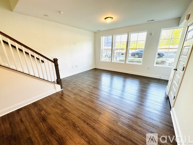 A room with wooden flooring and a staircase on the left side.