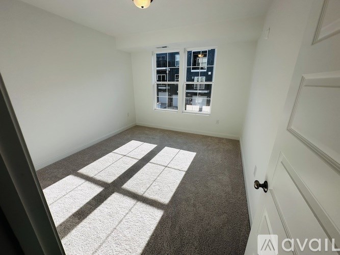 A room with a carpeted floor and a window with blinds.
