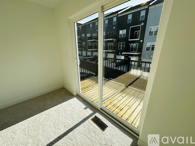 A room with a carpet floor and a glass door leading to a balcony with a railing.