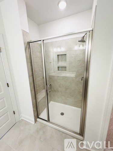 A shower stall with a glass door is in a white bathroom.