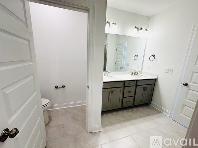 A bathroom with a toilet, sink, and cabinets.