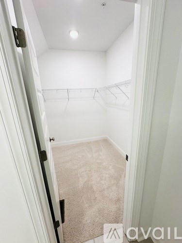 A white hallway with a carpeted floor and a door on the left.