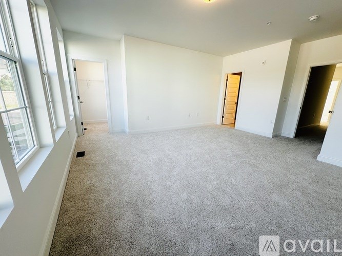 A spacious empty room with carpeted floor and white walls.