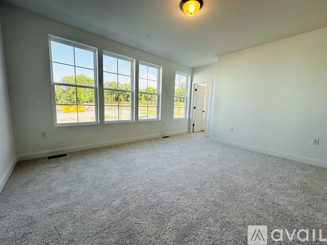 A spacious room with a carpeted floor, large windows, and a door.