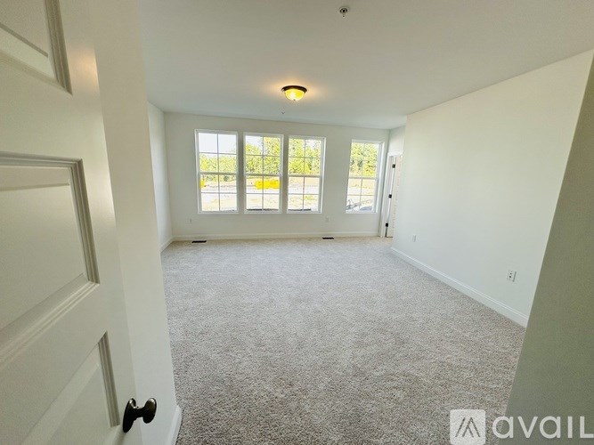 A room with a carpeted floor and a door on the left side.