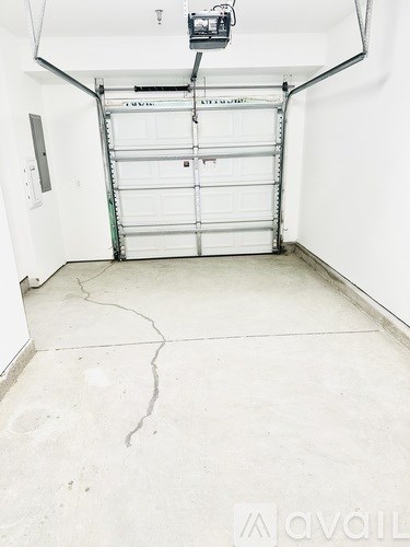 A white garage door is closed and there is a white wall behind it.