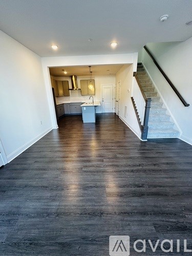 A spacious room with wooden floors and a staircase leading to another level.