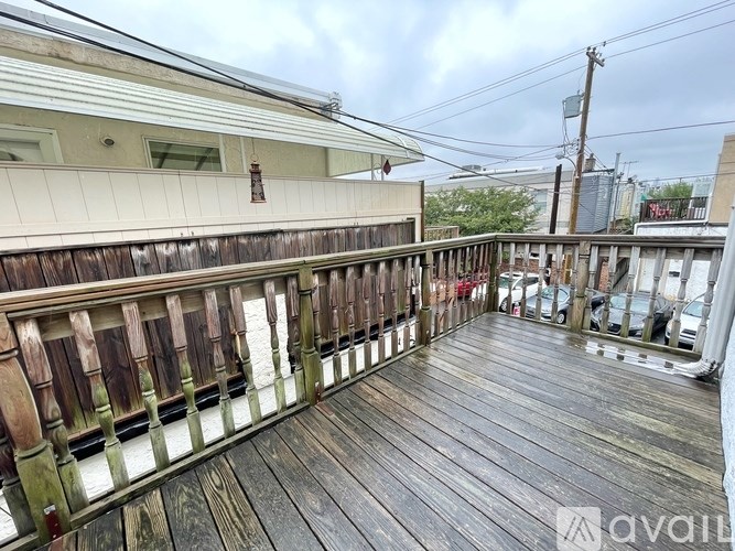 A wooden deck with a railing and a building in the background.