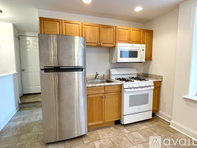 A kitchen with a stainless steel refrigerator, a white microwave, a white oven, and wooden cabinets.
