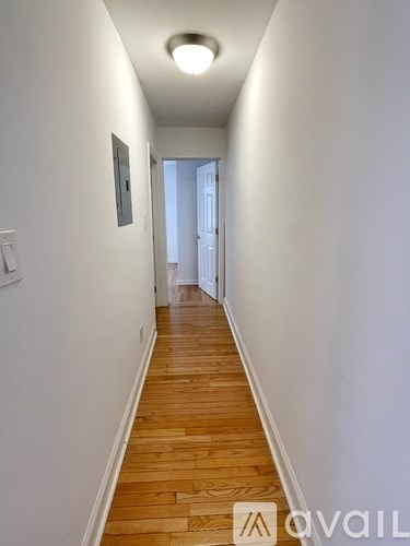 A long hallway with wood floors and white walls.