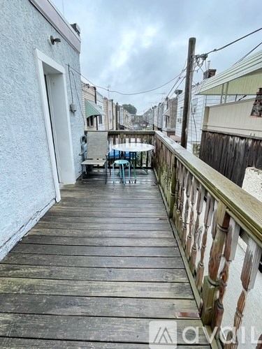 A wooden deck with a table and chairs is in front of a white building.