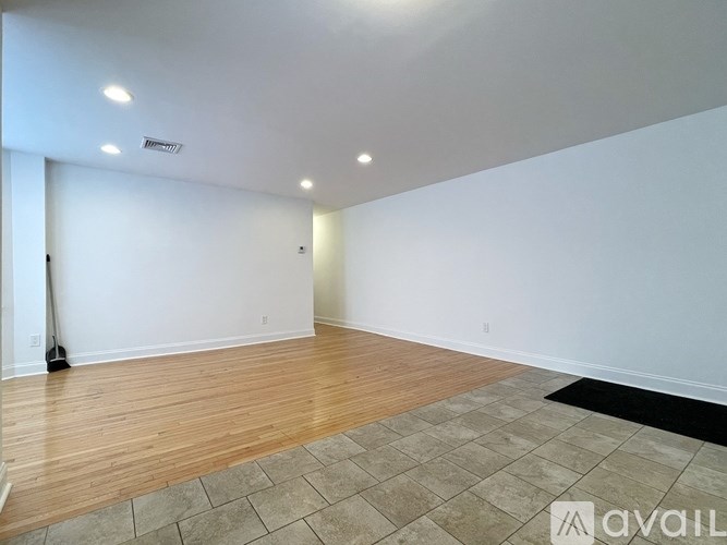 A room with wooden flooring and a black rug on the floor.