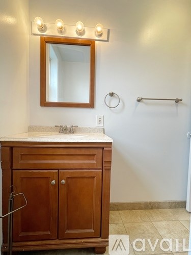 A bathroom with a wooden vanity and a mirror above it.