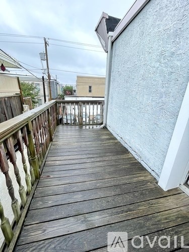 A wooden deck with a railing and a white wall.
