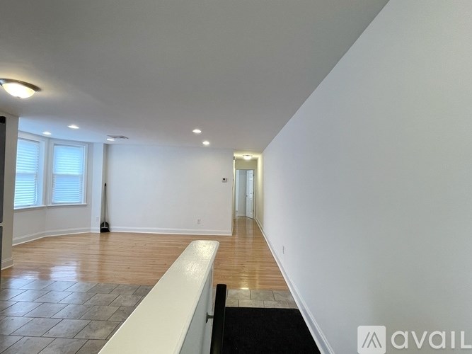 A long hallway with a black carpet and wooden floors.