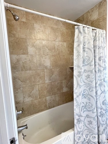 A shower with a curtain and a tub.