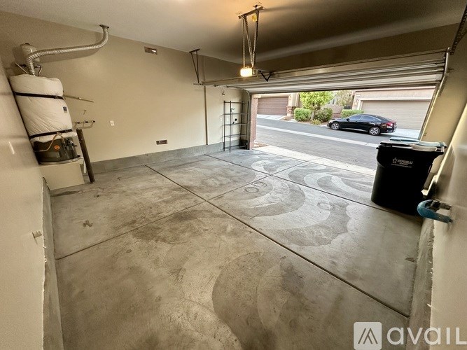 A garage with a concrete floor and a black trash bin.