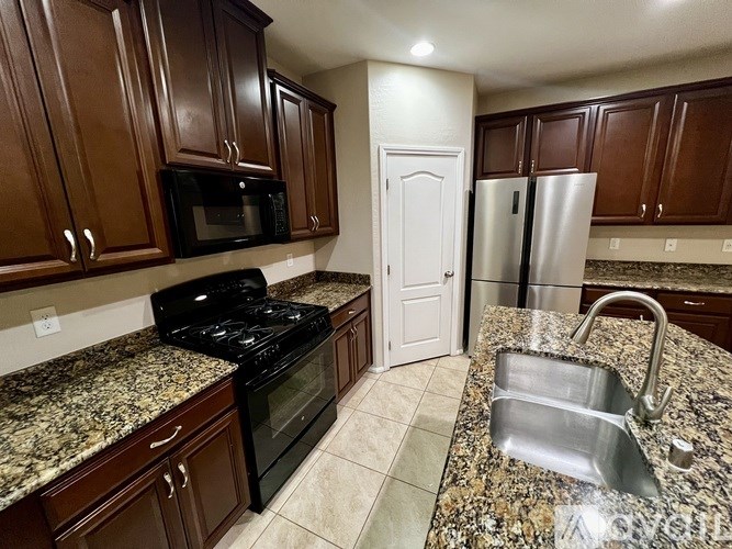 A kitchen with granite countertops and a stainless steel refrigerator.