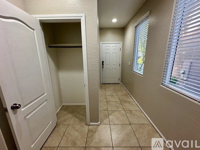 A white door is open to a hallway with a tiled floor.