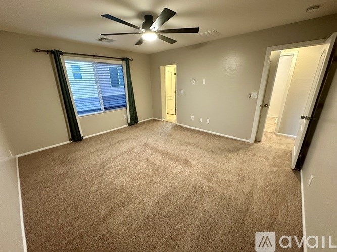 A room with a ceiling fan and carpeted floor.