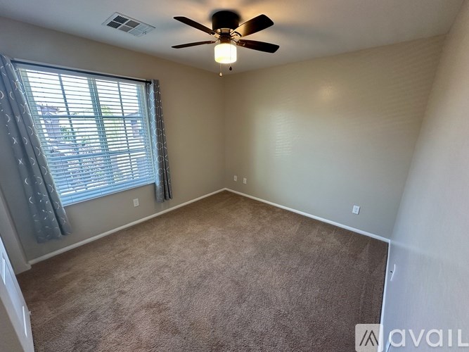 A room with a ceiling fan and carpeted floor.