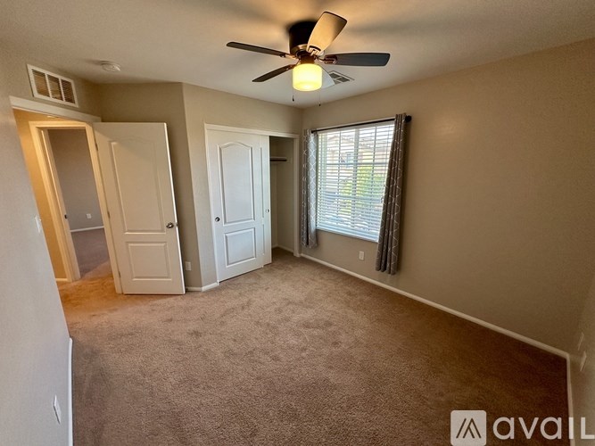 A room with a ceiling fan and carpeted floor.