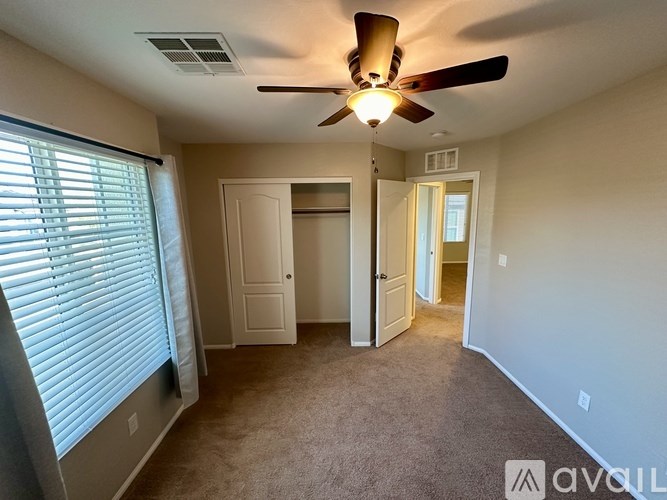 A room with a ceiling fan and carpeted floor.