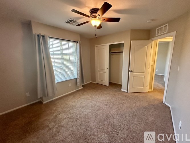 A living room with a ceiling fan and carpeted floor.