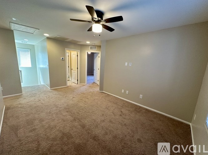 A room with a ceiling fan and carpeted floor.