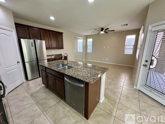 A kitchen with a granite countertop and a stainless steel refrigerator.