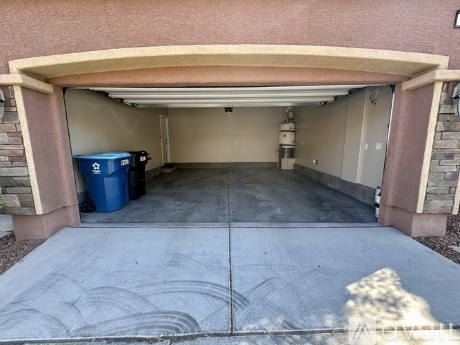 A garage with a blue bin and a grey trash can.