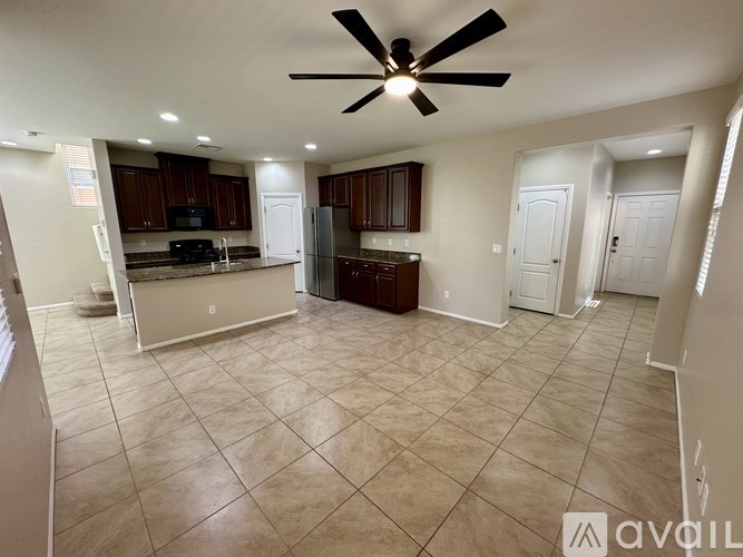 A spacious kitchen with dark brown cabinets and a black ceiling fan.